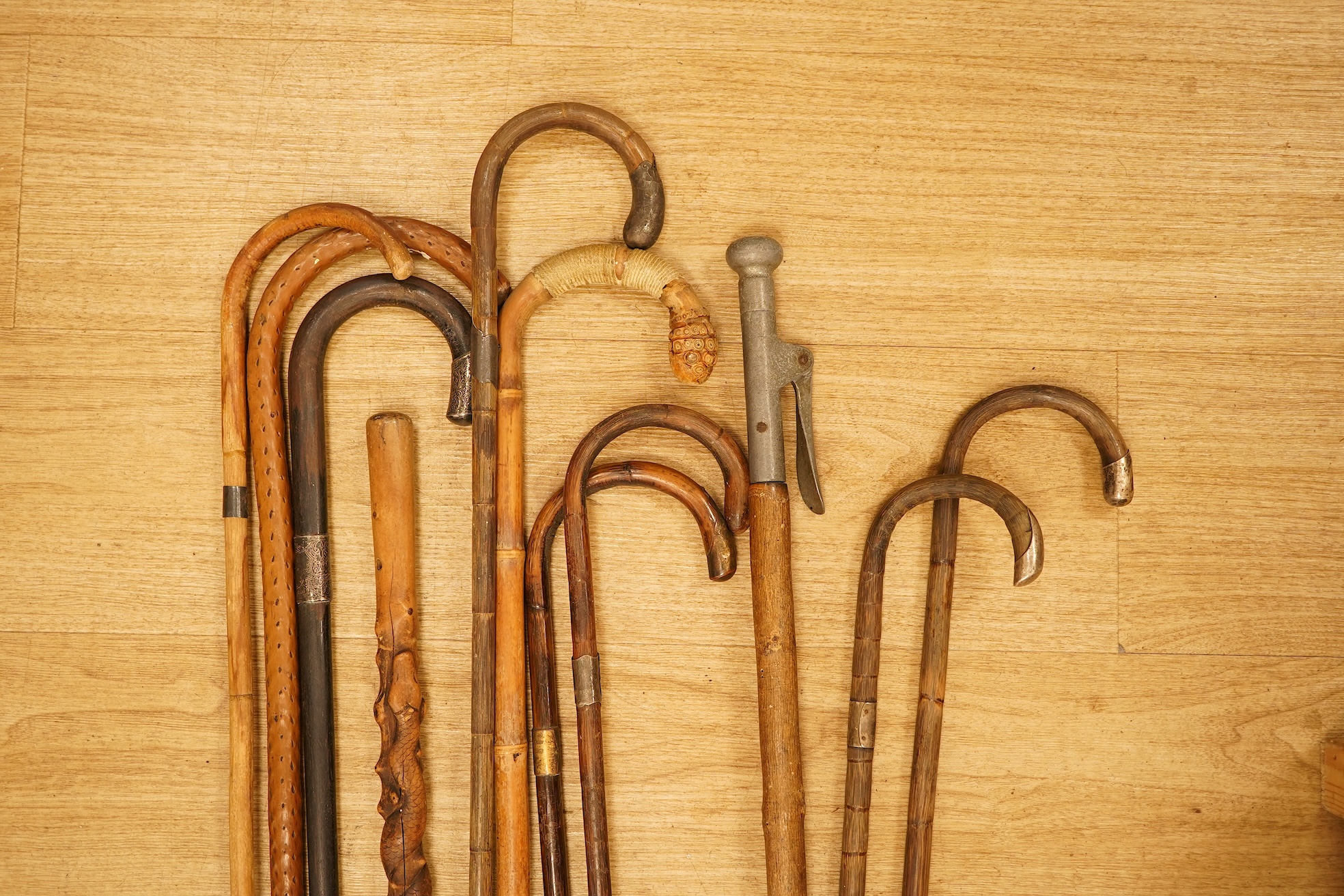 A collection of eleven carved walking sticks, some silver mounted